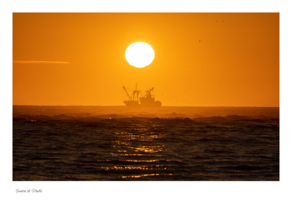 Sunrise at Howth, a fishing trawler under the rising sunset with a beautiful orange sky.
