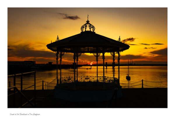 The Victorian Bandstand in Dun Laoghaire with a beautiful red sky and the sun setting in the centre of the bandstand.