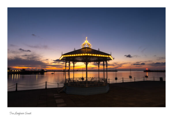 The Victorian Bandstand in Dun Laoghaire with a beautiful red sky and calm sea and the lights lit up on the band stand