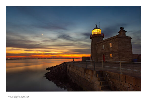 Howth Lighthouse at Sunset with a calm sea and a beautiful red sky